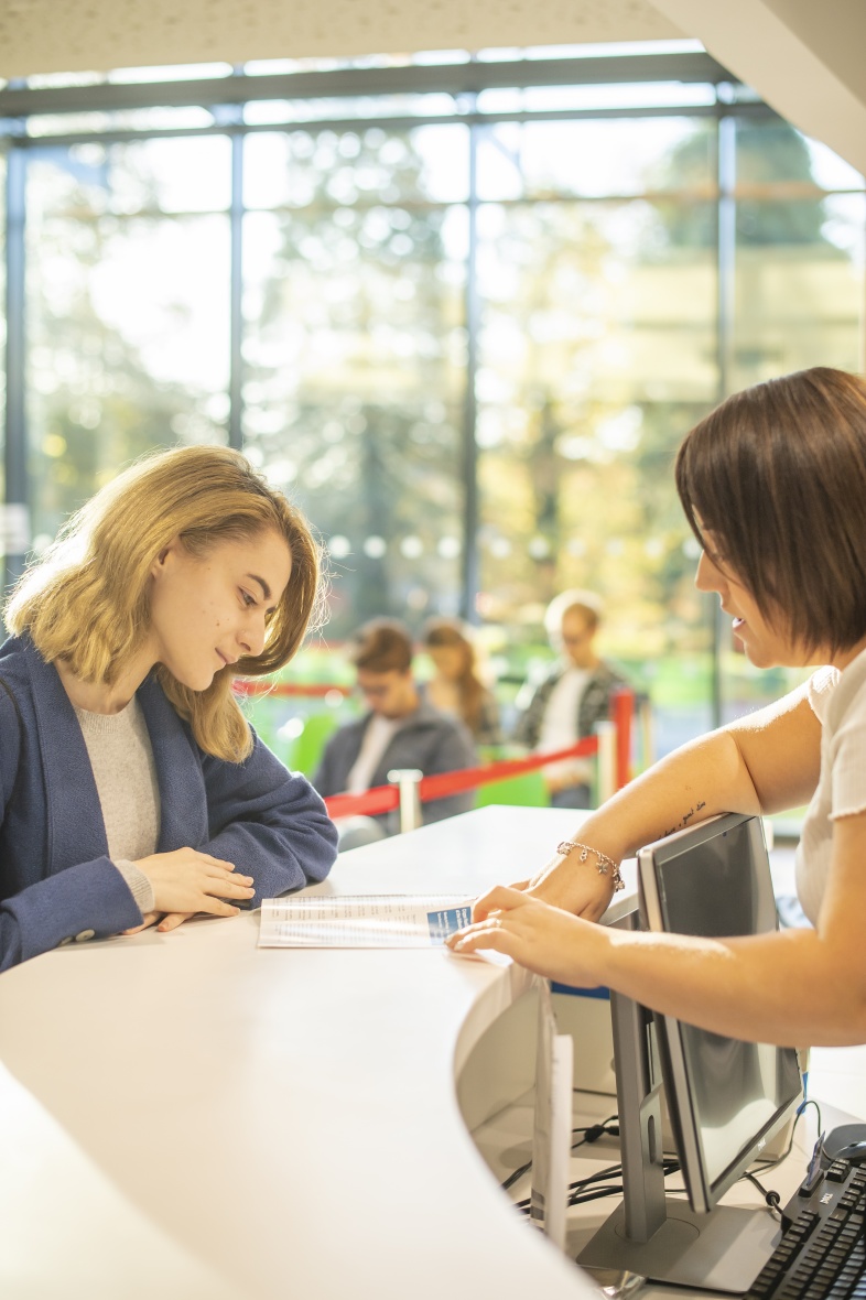 Student talking with a member of staff and reading information off a document