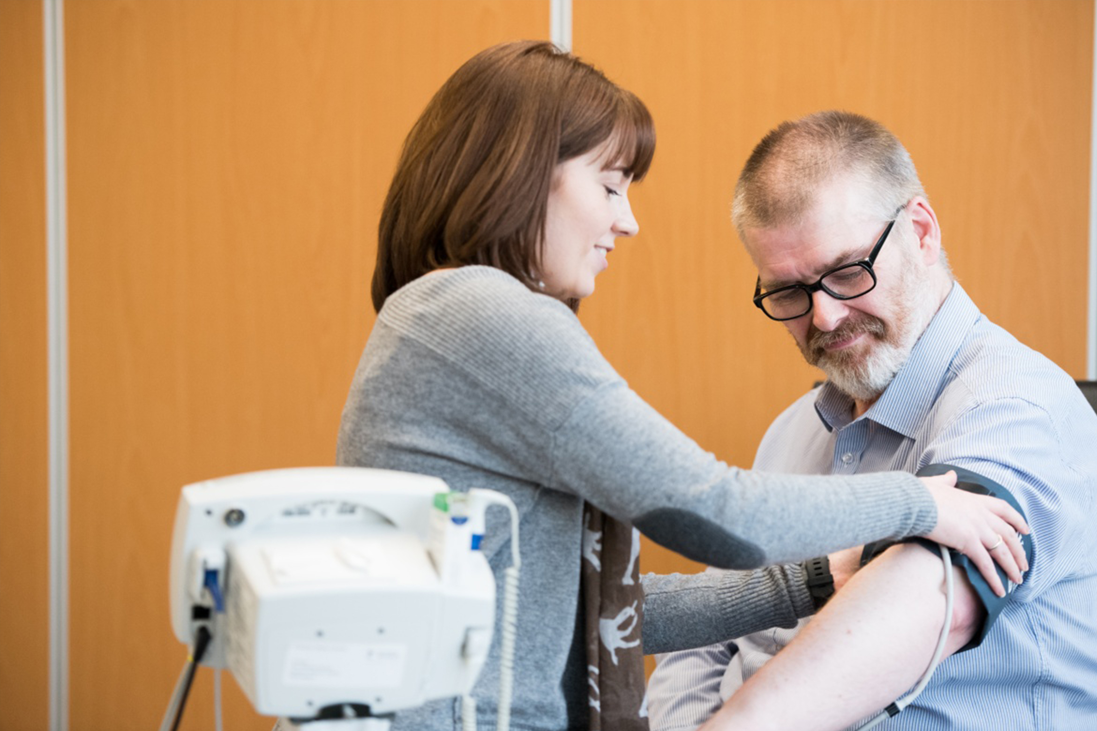 Postgraduate student putting blood pressure monitor on patient