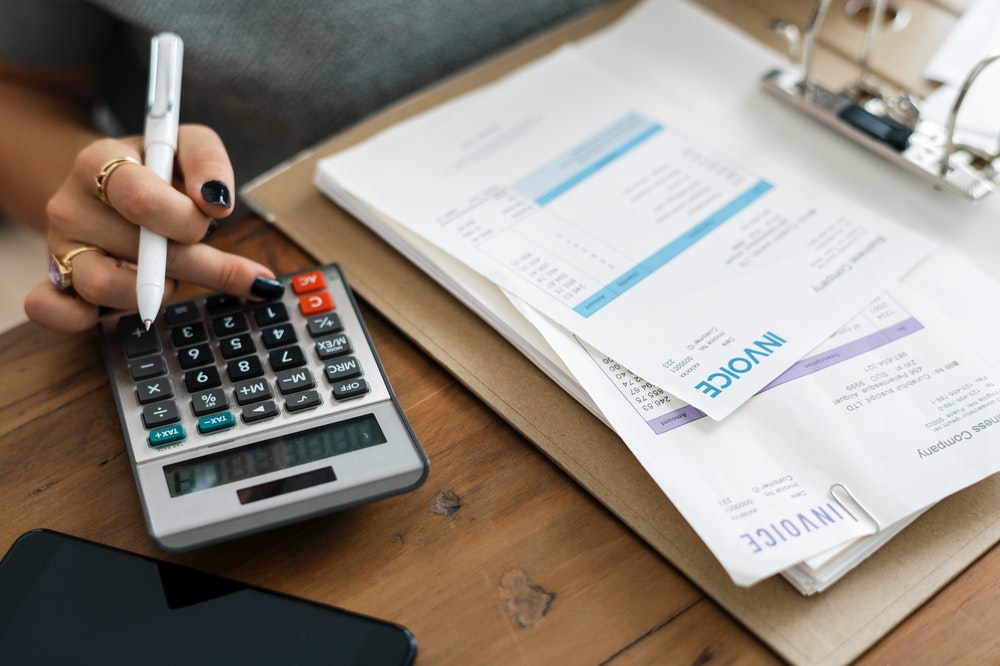 Woman holding pen while using calculator